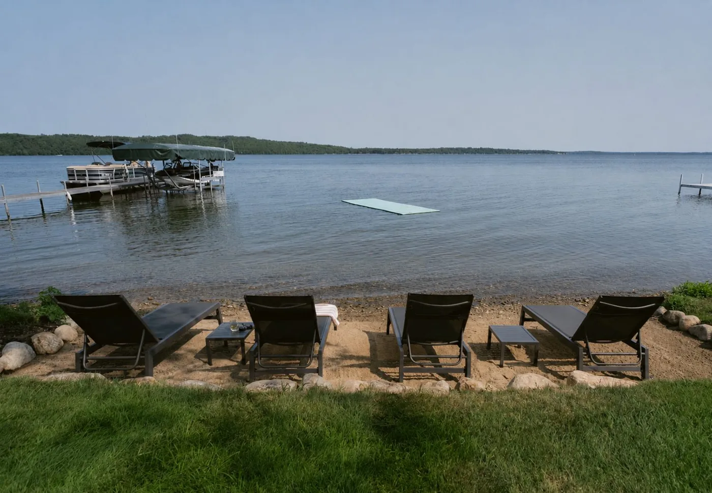 Sandy beach with loungers, dock, and swim raft